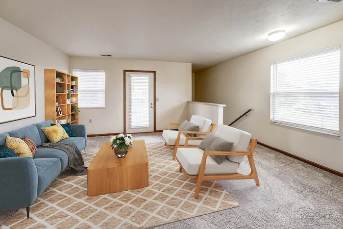 Bright and inviting living room boasting a chic modern design with a plush blue sofa, stylish armchairs, and a sleek wooden coffee table, ideal for relaxation and entertaining.