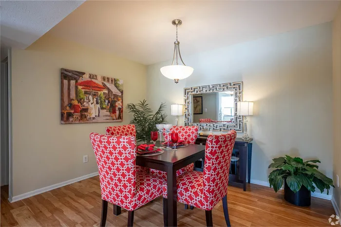 Inviting dining area featuring bold red patterned chairs, a stylish dark wood table, and elegant decor including a modern chandelier and vibrant artwork.