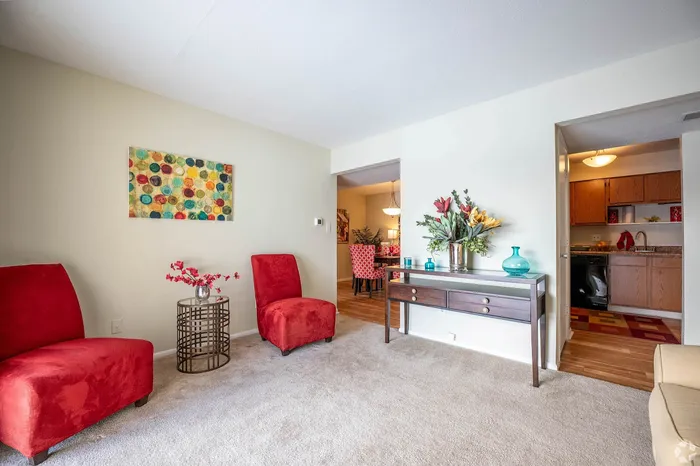 Charming living room with vibrant red chairs, modern decor, and access to kitchen and dining area.