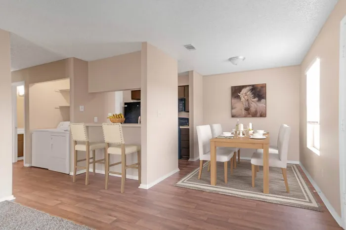 Charming open-plan dining and kitchen area with elegant decor, featuring a chic dining set and modern bar stools on polished hardwood floors.