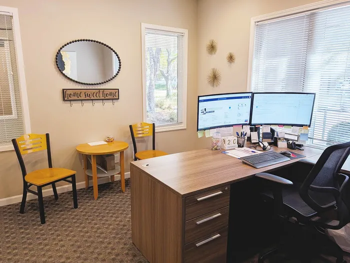 Inviting home office with a welcoming 'Home Sweet Home' sign, elegant wooden desk, dual monitors, and comfortable seating.