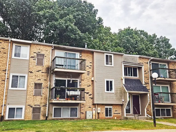 Inviting apartment building with charming balconies and lush greenery, perfect for comfortable living.