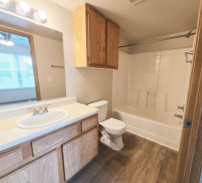 Bright and welcoming bathroom with modern sink, wooden cabinetry, and a pristine bathtub, illuminated by stylish lighting.