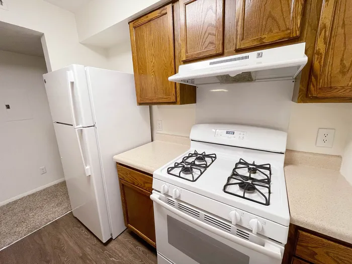 Cozy kitchen features modern white appliances, wooden cabinetry, and sleek countertops offering efficient space utilization.