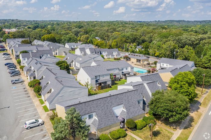 Charming aerial view of a serene residential community featuring modern townhouses, lush greenery, and a sparkling pool, perfect for a peaceful lifestyle.