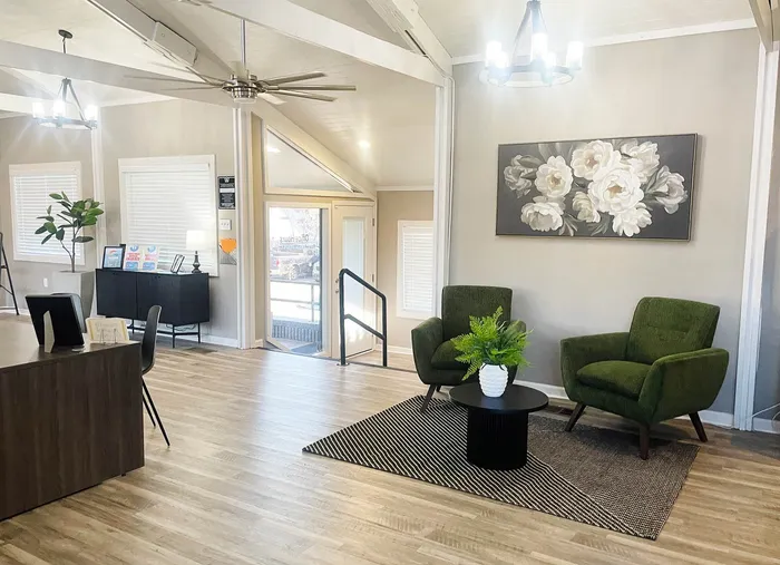 Inviting apartment lobby with elegant modern decor, featuring plush green armchairs, a sleek coffee table with a vibrant plant, and chic lighting fixtures.