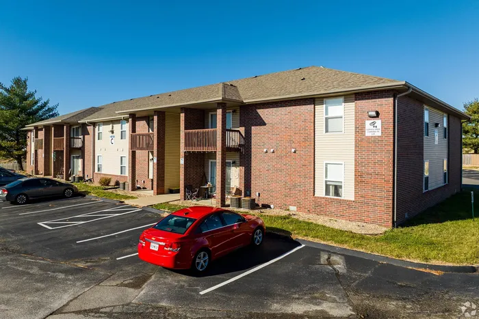 Inviting brick apartment complex with private balconies and convenient parking, nestled in a serene neighborhood.