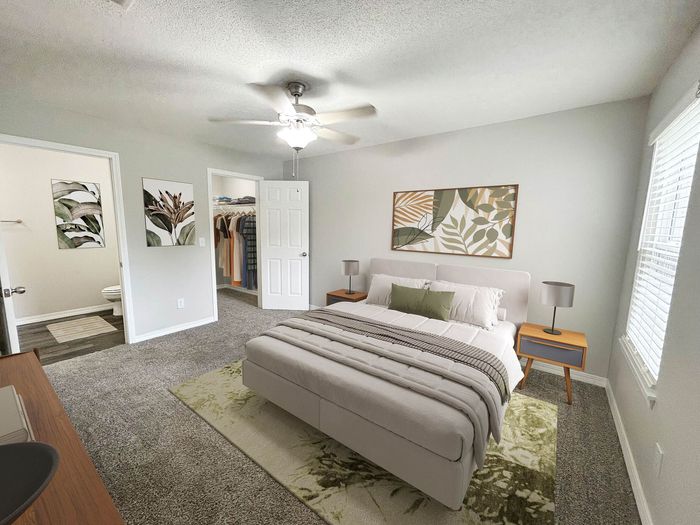 Inviting bedroom with neutral tones, featuring a plush bed, elegant artwork, and a walk-in closet. Natural light streams in through large windows, creating a warm and relaxing atmosphere.