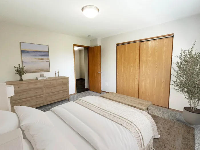 Bright and cozy bedroom with elegant decor, featuring a comfortable bed, stylish dresser, and ample closet space. Natural light enhances the room's serene ambiance.