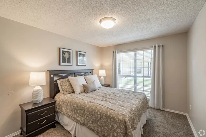Inviting bedroom with cozy bed, elegant decor, and ample natural light from a large window.