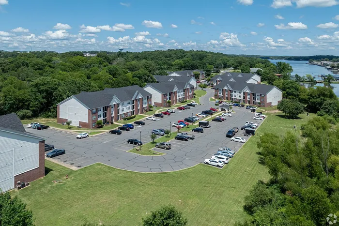 Charming apartment complex with stunning lake views, surrounded by lush greenery and ample parking.