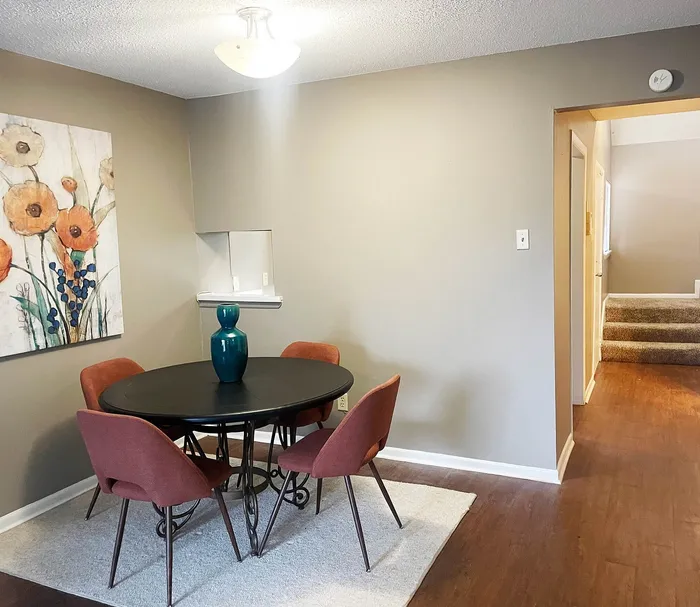 Cozy dining area with chic table and stylish chairs, complemented by vibrant floral artwork and warm lighting, perfect for intimate gatherings.