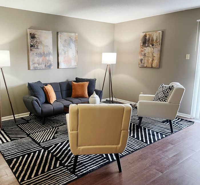 Chic and modern living room with stylish decor, featuring a cozy sofa, accent chairs, and abstract art, creating an inviting atmosphere.