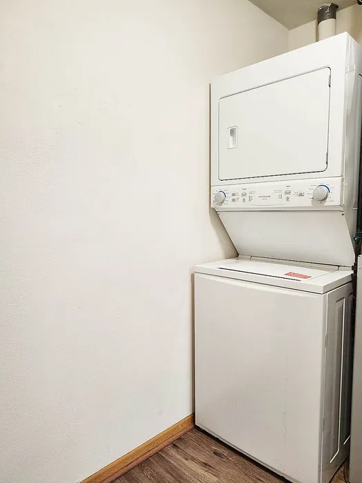 Compact laundry area featuring an efficient stacked washer and dryer set against a sleek white wall.