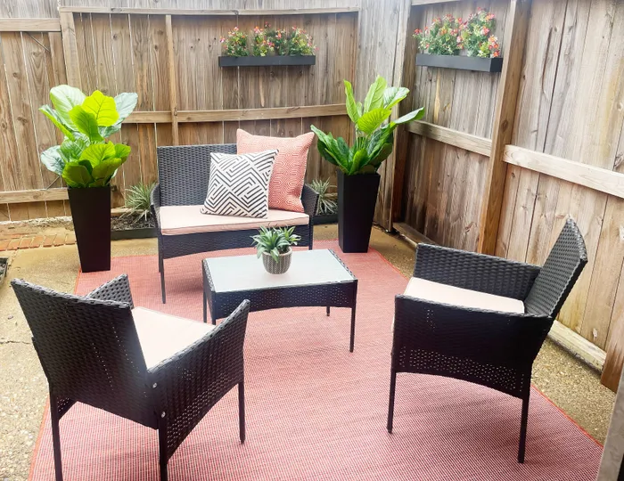 Charming outdoor patio featuring modern wicker furniture, colorful cushions, and lush green plants, perfect for relaxation and entertaining.