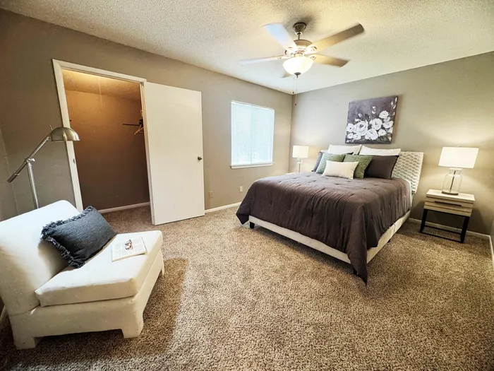 Cozy bedroom with plush carpeting, featuring a comfortable queen bed, stylish decor, and ample natural light.