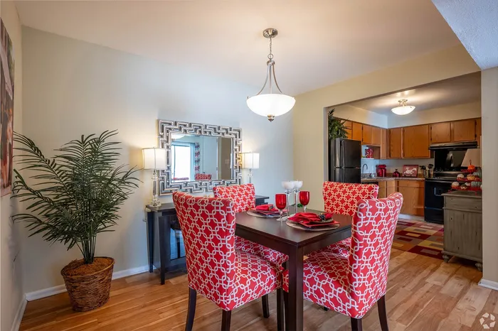 Inviting dining area with vibrant red chairs, contemporary lighting, and a view into a modern kitchen, perfect for entertaining.