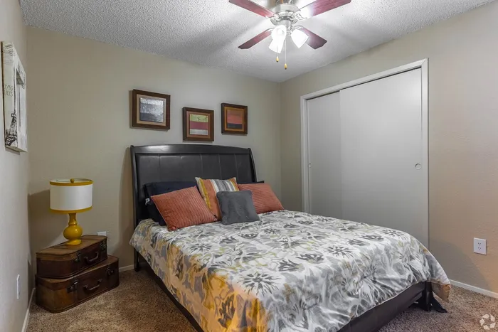Cozy bedroom with stylish decor, featuring a plush bed with colorful pillows and framed art on the walls.