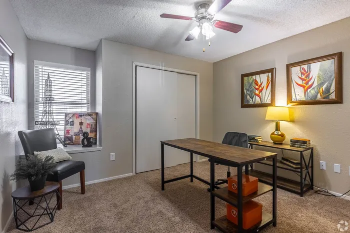 Elegant home office with plush carpeting, modern desk, and tasteful decor, including vibrant wall art and stylish lighting.