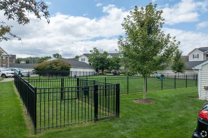 Charming apartment complex surrounded by lush greenery and secure black metal fencing, offering a serene environment for residents.