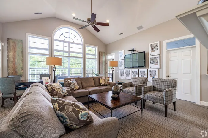 Bright and stylish living room with vaulted ceilings, modern furniture, large arched windows, and elegant decor.