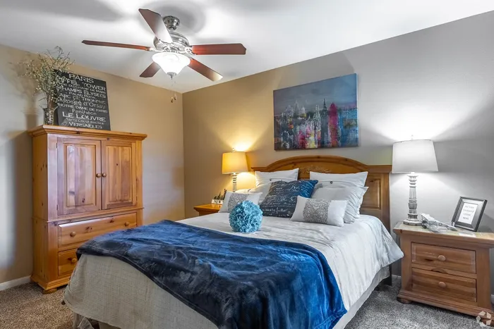 Inviting bedroom featuring a plush bed with vibrant blue accents, wooden furniture, and soft ambient lighting.