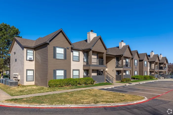 Charming apartment complex with modern design, spacious balconies, and inviting outdoor spaces under a clear blue sky.