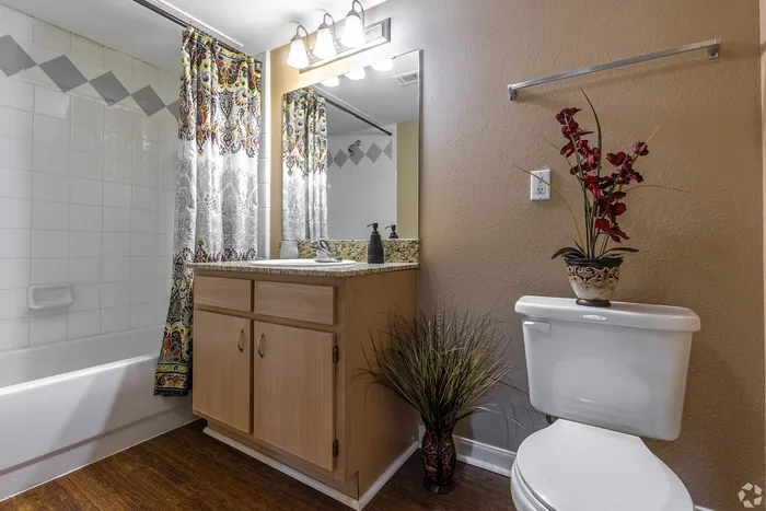 Elegant bathroom with stylish patterned shower curtain, modern vanity, and decorative plant accents creating a welcoming ambiance.