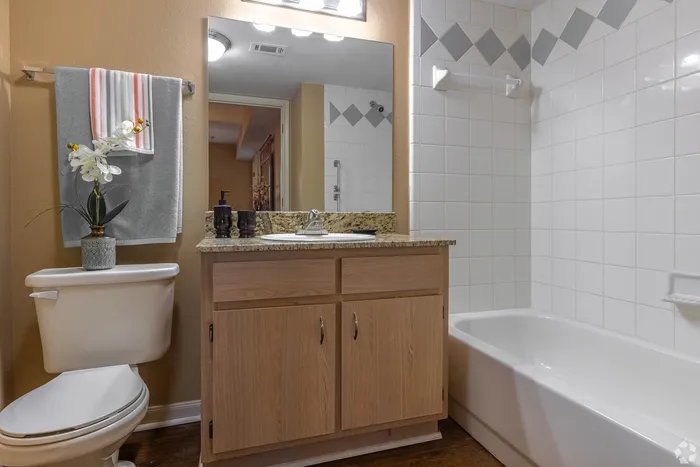 Elegant bathroom featuring granite countertops, stylish wood cabinetry, and a pristine white tile shower area, complete with modern fixtures and decorative accents.