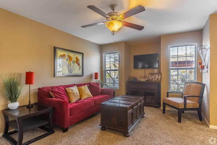 Cozy living room with a vibrant red sofa, elegant wooden furniture, and warm lighting, perfect for relaxation and entertaining.