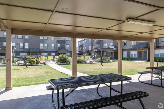 Charming outdoor patio area featuring picnic tables and lush greenery, perfect for relaxation and social gatherings.