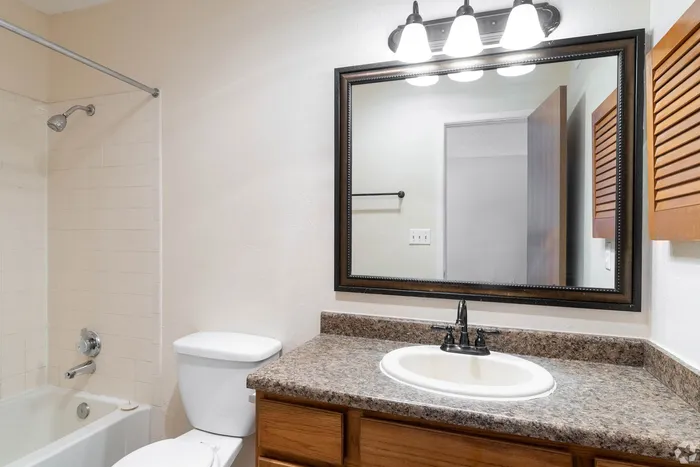 Charming bathroom with elegant wood accents, large vanity mirror, and warm lighting for a cozy atmosphere.