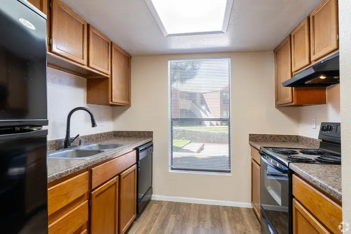 Inviting kitchen with elegant wooden cabinetry, modern appliances, and abundant natural light from a large window.