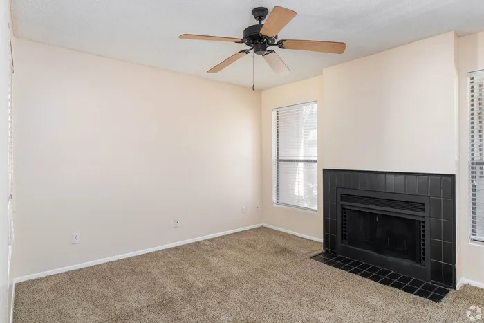 Bright, inviting room with a cozy fireplace and stylish ceiling fan, perfect for a relaxing retreat.
