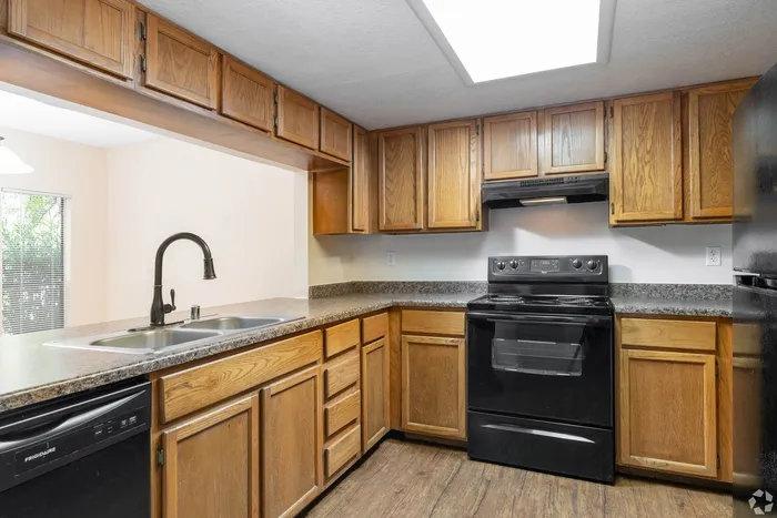 Charming kitchen with elegant wooden cabinetry, sleek black appliances, and a modern double sink, perfect for culinary enthusiasts.