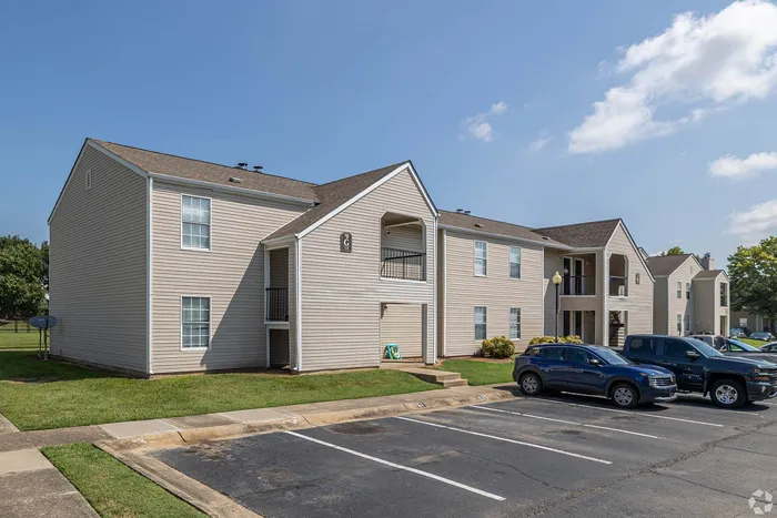 Inviting two-story apartment building with ample parking, nestled in a serene neighborhood and bathed in sunlight, perfect for modern living.