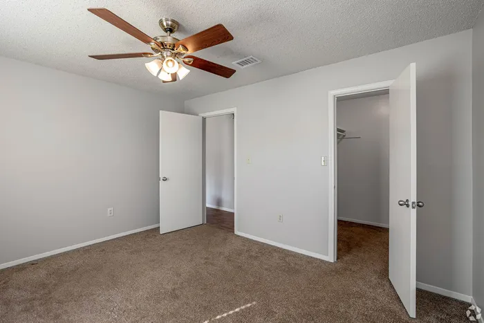 Bright and airy bedroom featuring soft carpet flooring, contemporary fan, and a walk-in closet.