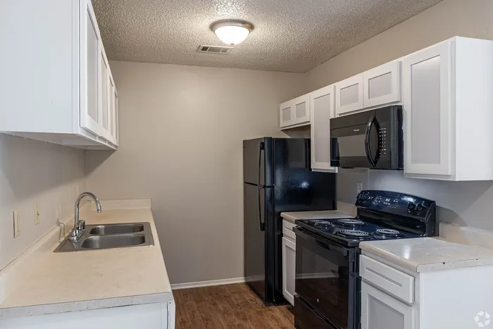 Modern kitchen with sleek black appliances, ample cabinetry, and a double sink, ideal for culinary adventures.