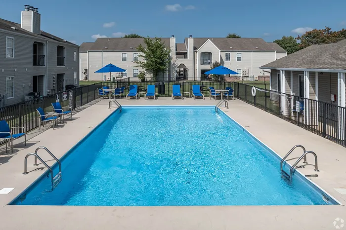 Inviting pool area with modern lounge chairs and umbrellas, surrounded by charming apartment buildings, perfect for relaxation and leisure.