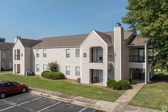 Charming two-story apartment building with private balconies and lush landscaping in a serene setting.