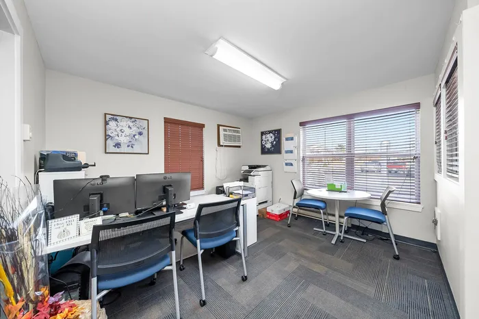 Bright office space with modern decor, featuring large windows, sleek workstations, and a cozy meeting area.