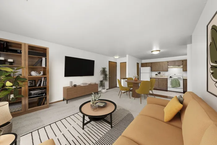 Bright and inviting living space with modern furnishings, showcasing a warm-toned sofa, sleek dining area, and a fully equipped kitchen with wooden cabinetry.