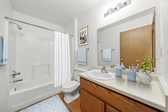 Bright, modern bathroom featuring a sleek white bathtub, stylish wood vanity, and elegant wall art, perfect for relaxation.
