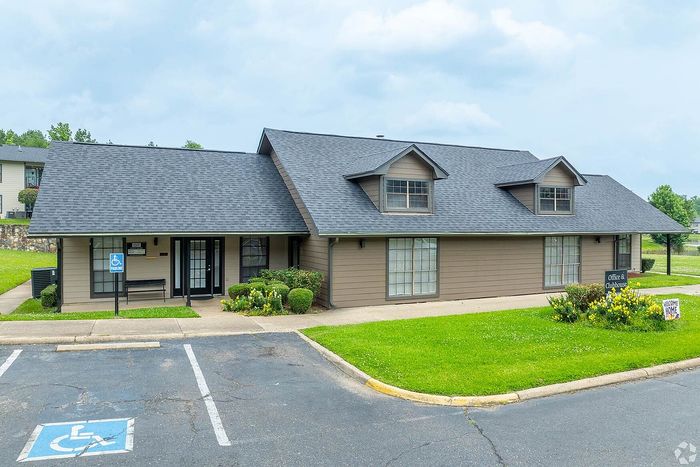 Charming office and clubhouse building with a welcoming front lawn and accessible parking in a serene neighborhood setting.