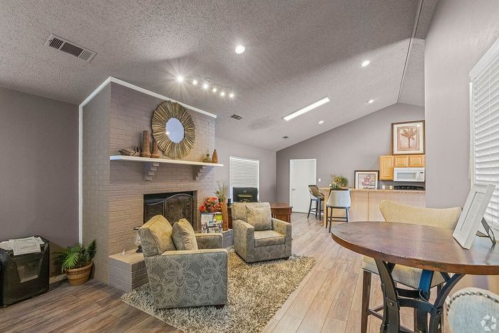 Elegant open-concept living space featuring a cozy fireplace, comfortable seating, and a stylish kitchen with bar stools for a welcoming atmosphere.