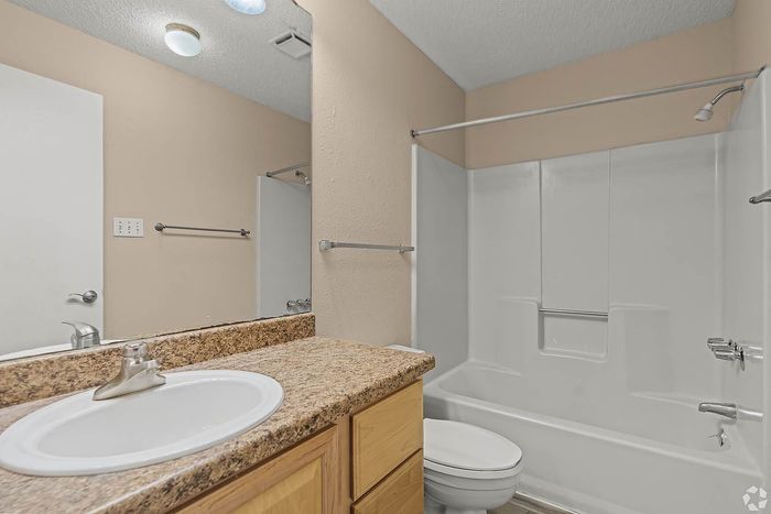 Elegant bathroom showcasing a granite countertop sink, modern fixtures, and a pristine bathtub.