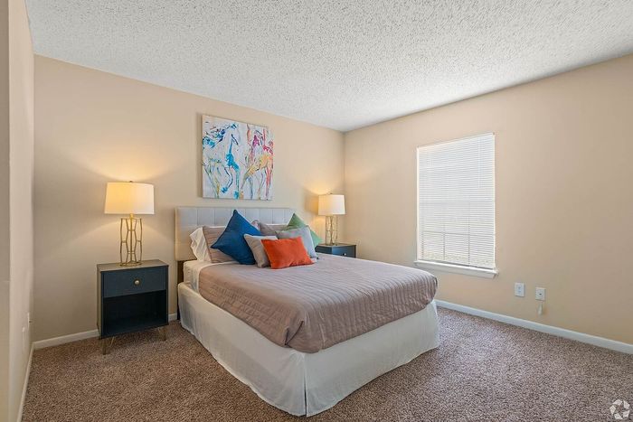 Inviting bedroom with plush carpeting, elegant decor, and soft lighting, perfect for relaxation.