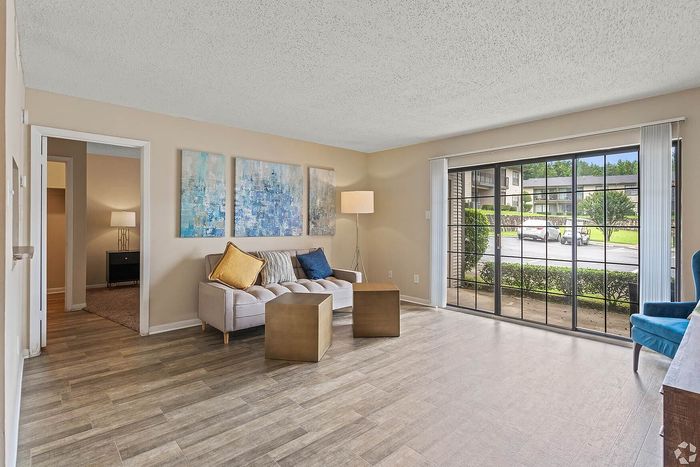 Inviting living room with large windows, modern artwork, and plush seating, offering a bright and airy atmosphere.