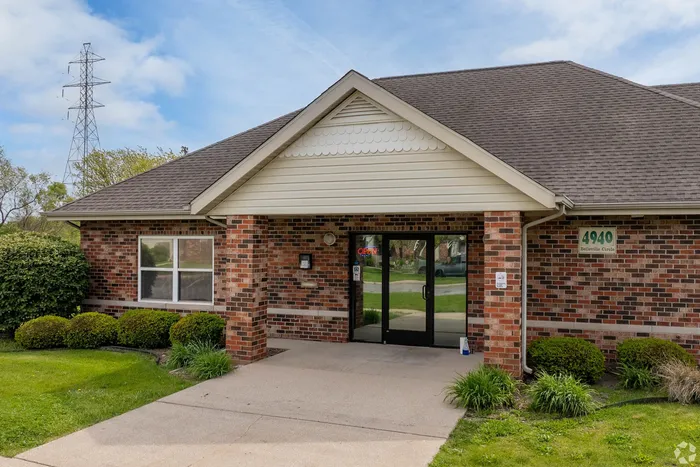 Inviting brick apartment entrance with manicured landscaping and a welcoming pathway, perfect for a cozy home setting.