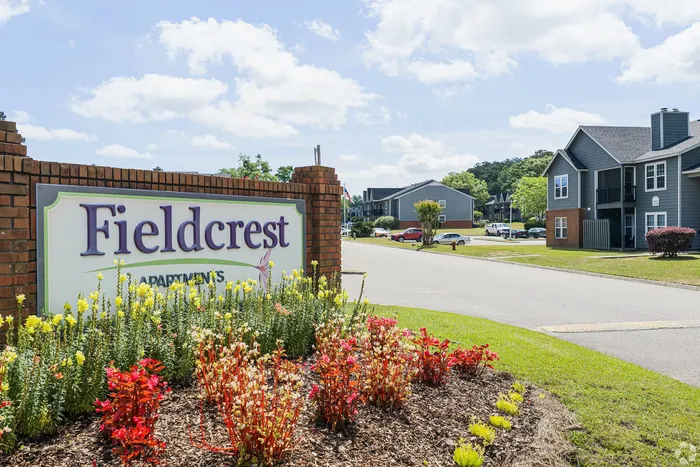 Inviting entrance to Fieldcrest Apartments, featuring vibrant landscaping and modern housing units in a tranquil setting.